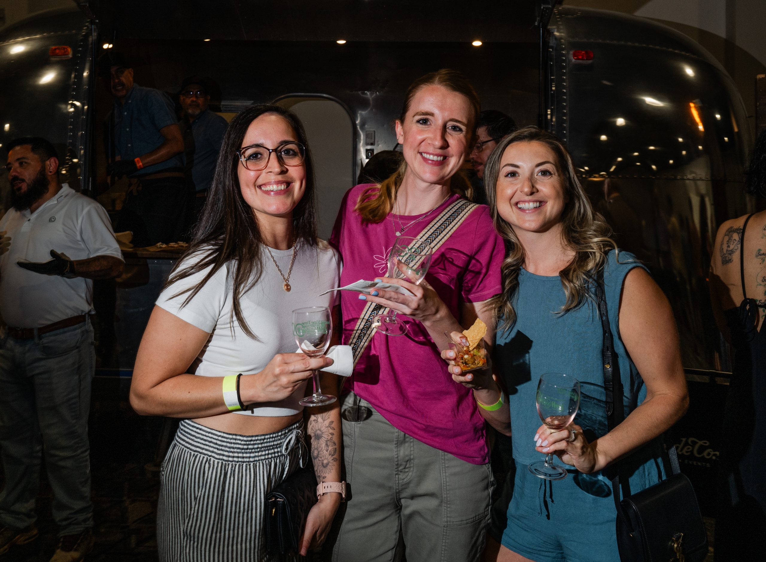 Three Ladies Holding Wine Glasses and Food From Goode Co. Catering