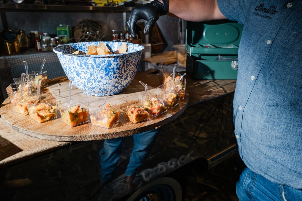 Little clear cups full of salsa with spoons surrounding a big bowl of tortilla chips