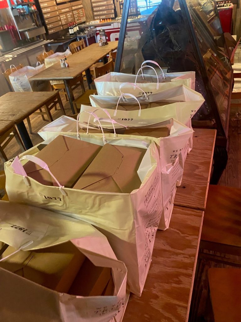 A long row of Goode Co. logo bags full of boxed lunches ready to be delivered or picked up.