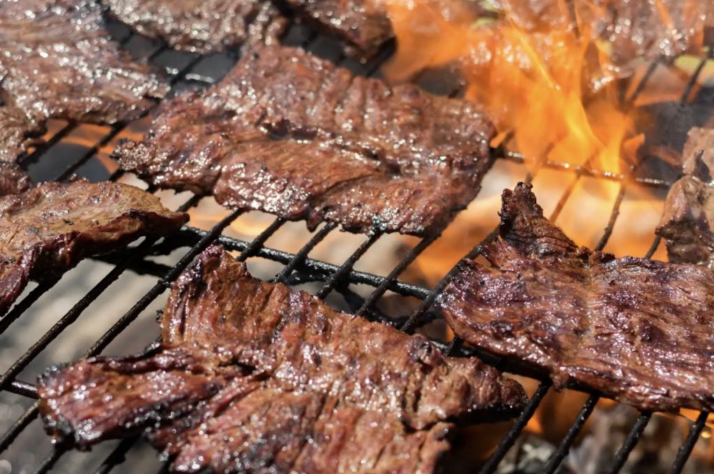 Flames from a grill shooting up with ribs bbqing